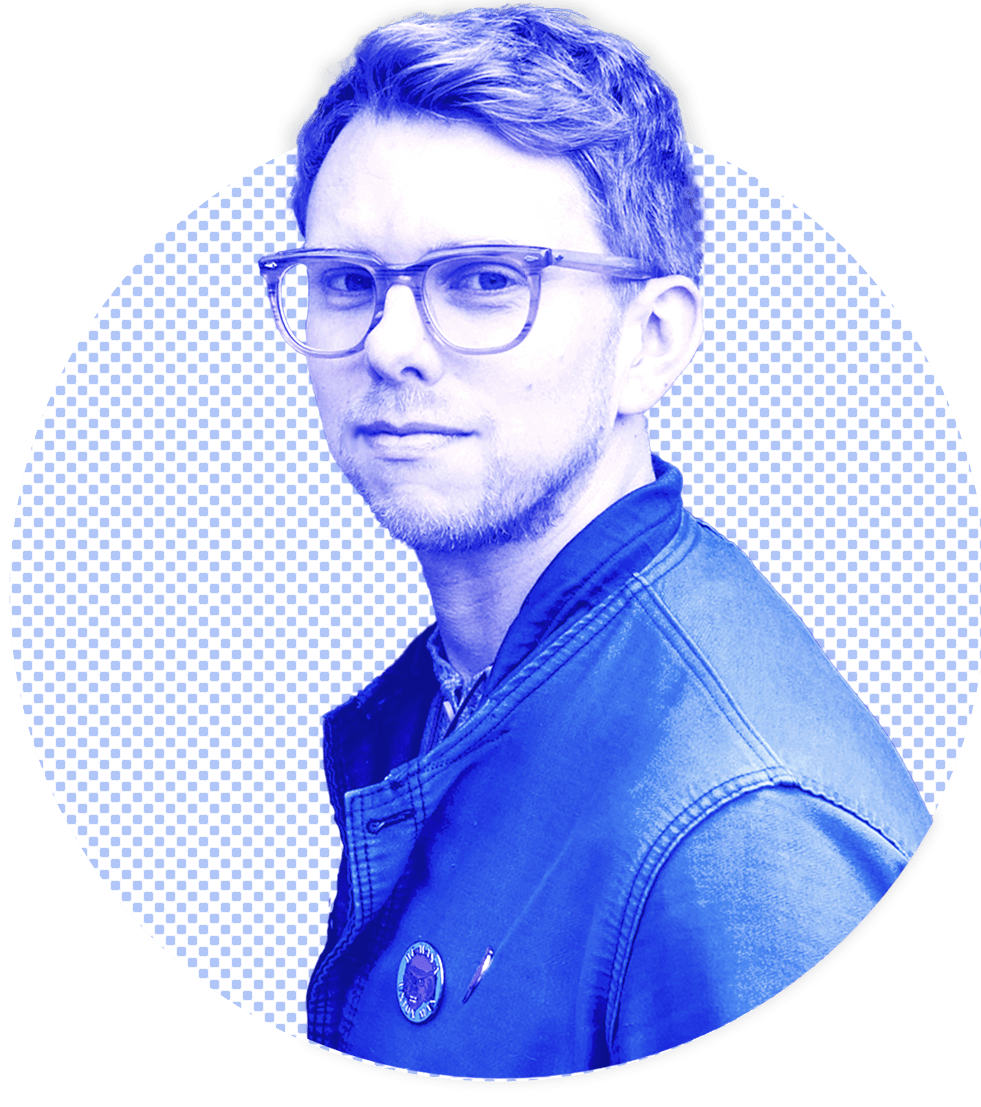 Photograph: Matthew sitting in a park in front of a domed greenhouse.
