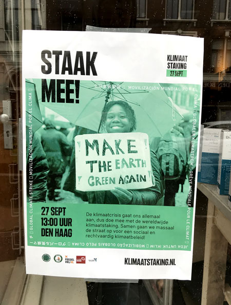 Dutch poster for a local Global Climate Strike event hanging in a shop window in Amsterdam.